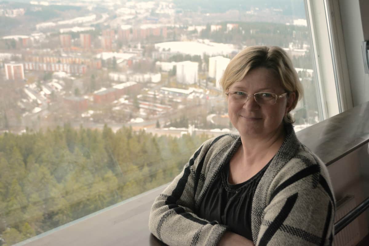 Tiina Heinonen seisoo Puijon tornin kahvilassa Kuopio taustallaan.