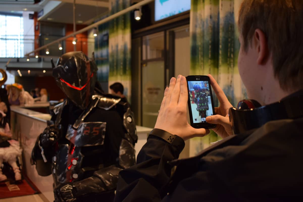 Poika kuvaa robotiksi pukeutunutta cosplay-harrastajaa.