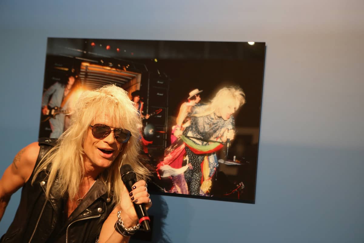 Michael Monroe poseeraa Justin Thomas ottaman valokuvan edessä. Valokuva otettu Up Around the Bend -musiikkivideon kuvauksissa 1984.