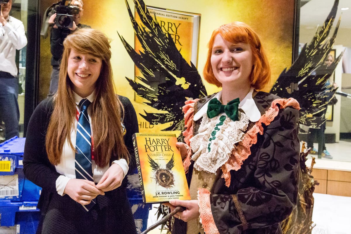 Kaksi naista joista toinen pitelee Harry Potter -kirjaa käsissään.