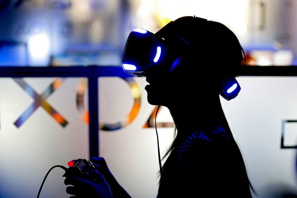 Henkilö virtuaalilasit päässään ja konsoliohjain käsissään.
