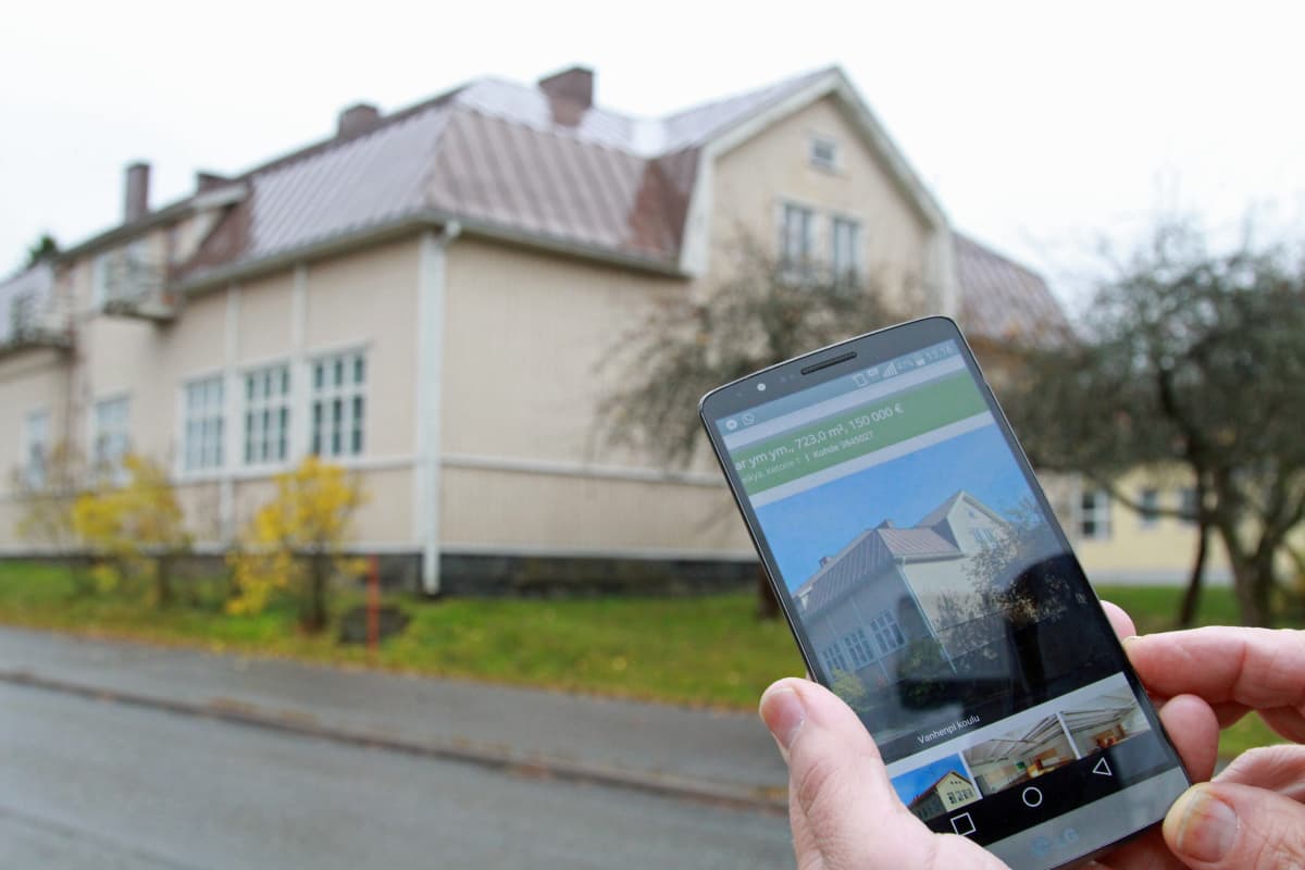 Keikyän koulun edustalla katsotaan myynti-ilmoitusta kännykän näytölltä.