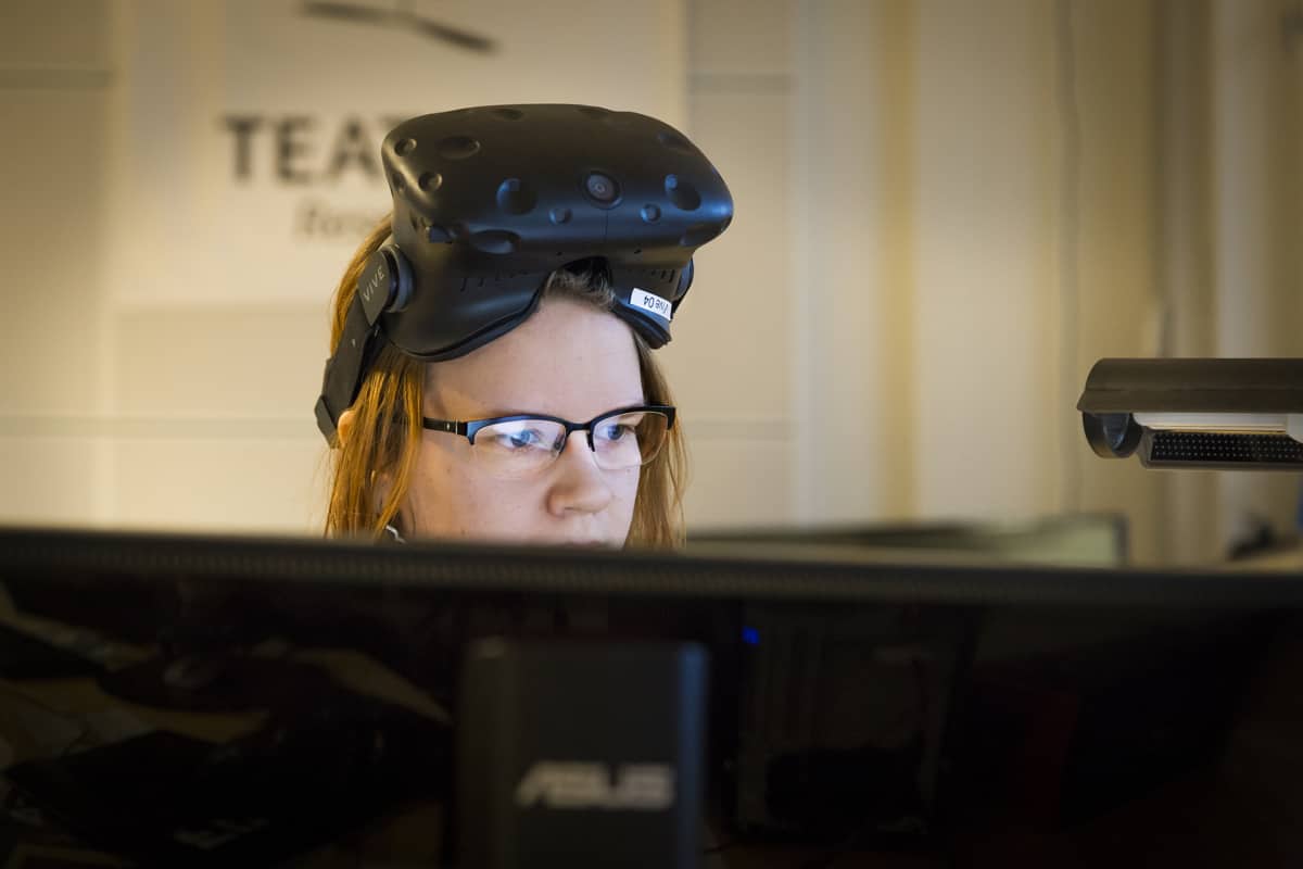 Naine virtuaalilasit otsalla tietokoneen ääressä.