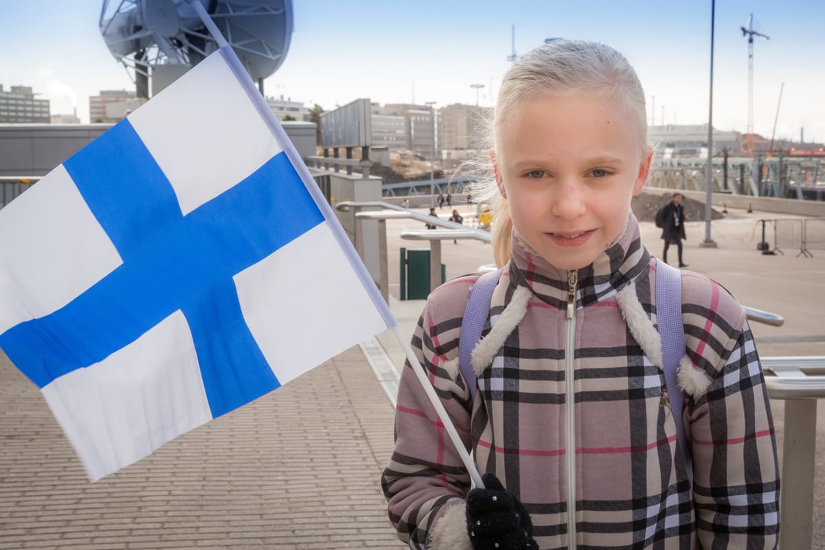 Suomalainen pikkutyttö Suomen lippu kädessä.