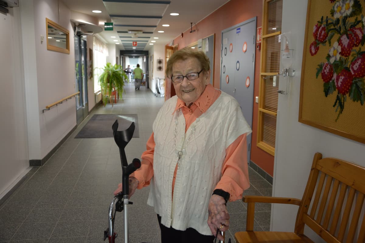 vanha rouva rollaattorin kanssa palvelutalon käytävällä