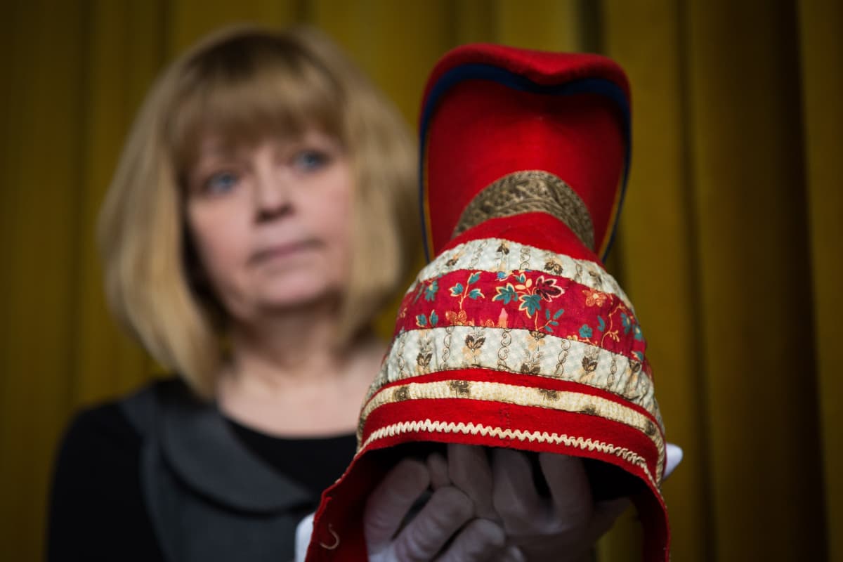 Kansallismuseon intendentti Raila Kataja pitelee kädessään saamelaista sarvilakkia.