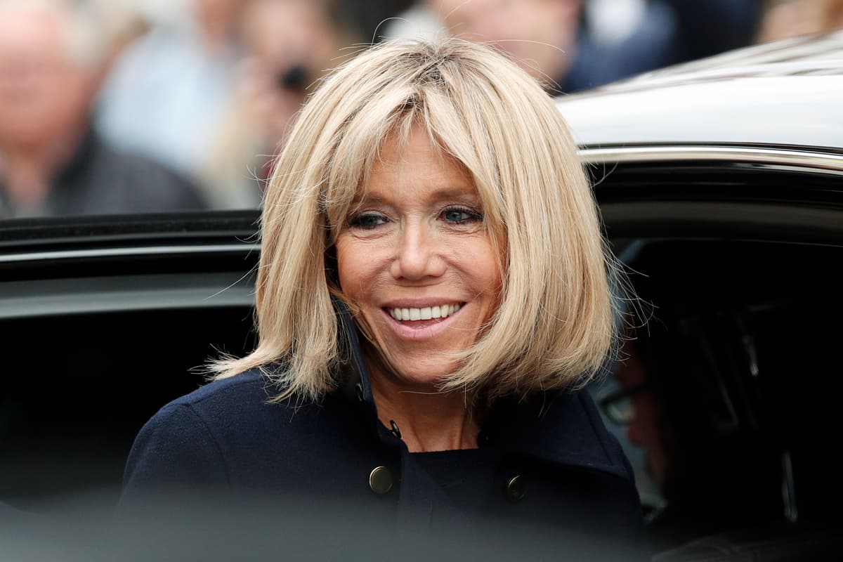 Brigitte Trogneux nousemaassa auton kyytiin hymyillen kameroille.