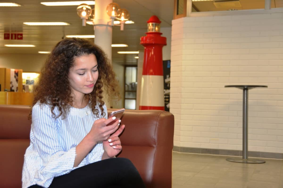 Amanda Rahmani istuu kaupungintalon aulassa kännykkä kädessään.