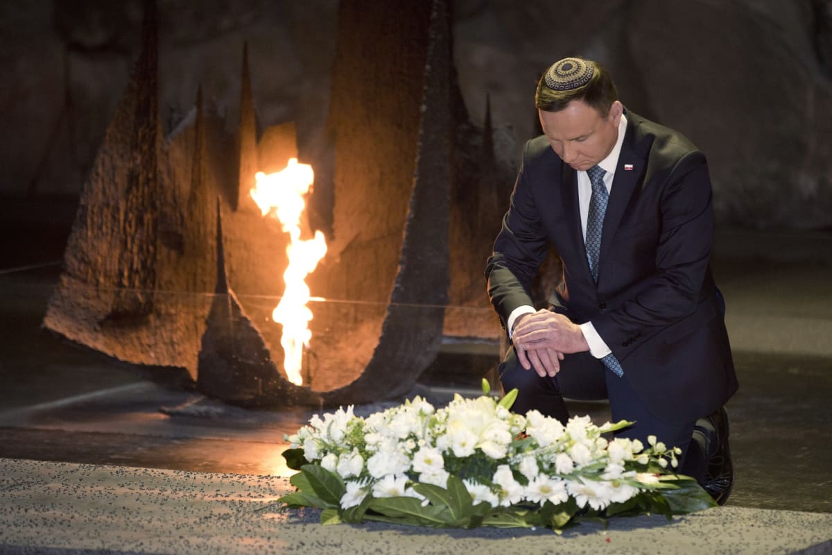 Kipapäinen Duda hiljentyy seppeleen vieressä.
