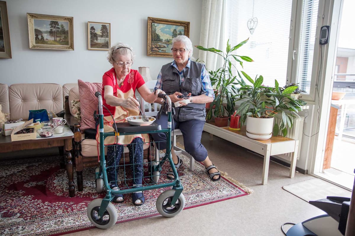 Lähihoitaja Leila Kantanen katsoo vierestä kun Sirkka Arola ruokailee kotonaan.