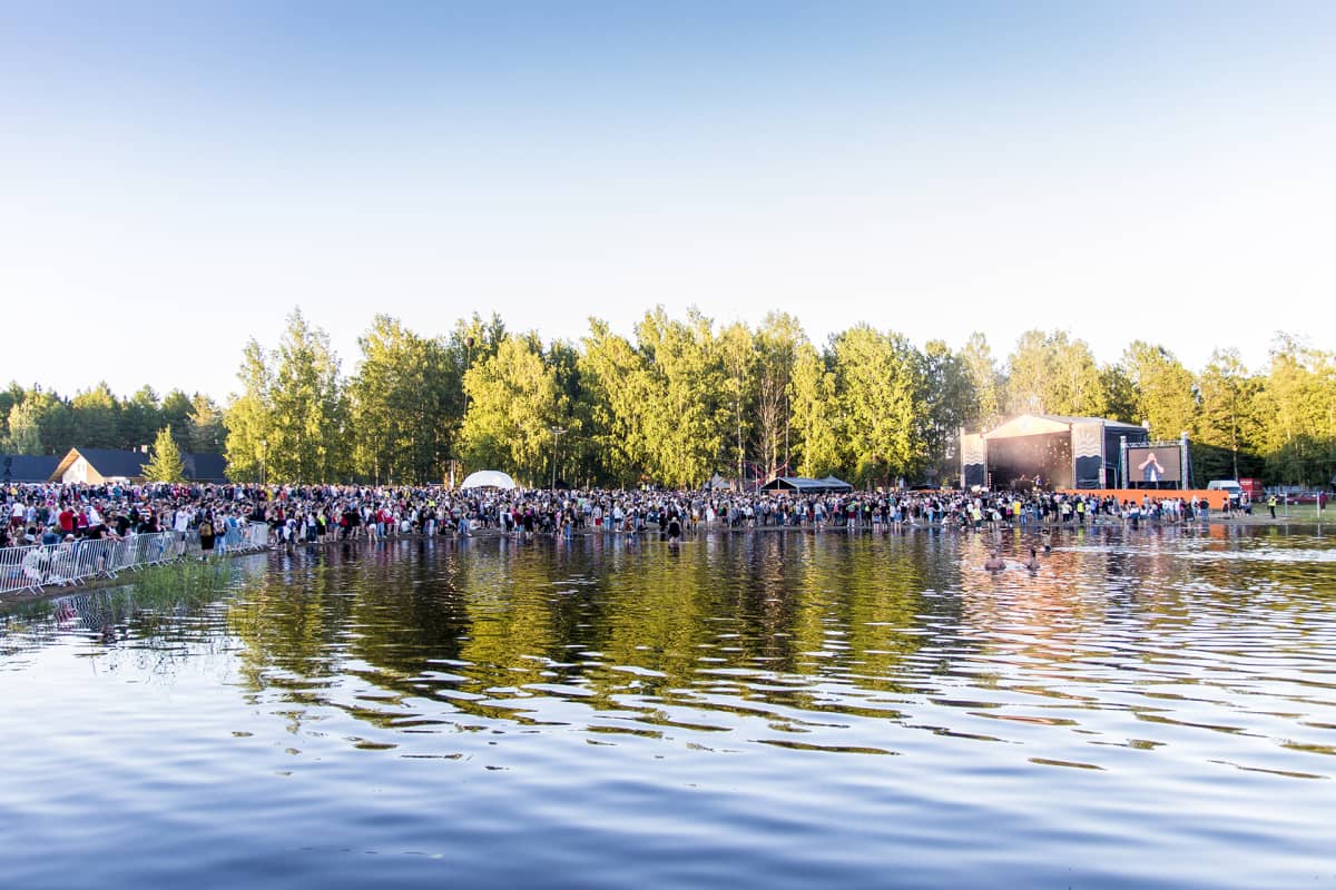 ihmisiä järvenrannassa ja esiintymislava