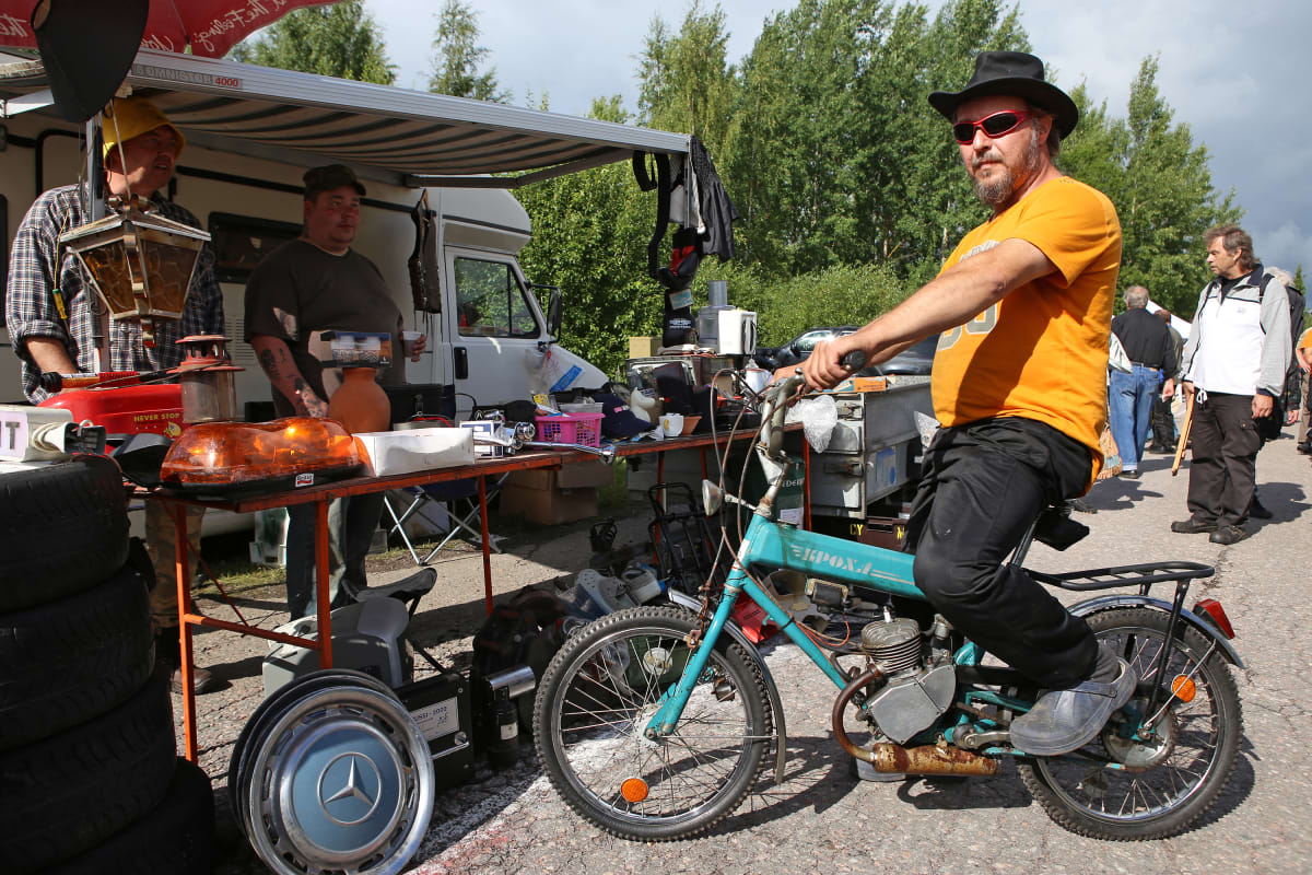 Mies istuu vanhan apumoottoripolkupyörän satulassa.
