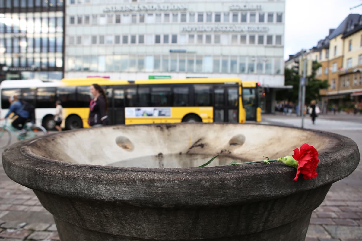 Punainen ruusu asetettuna suuren kukkaruukun reunalle.