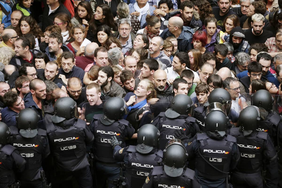 Mellakkapoliisit ja aktivistit ottavat yhteen äänestyspaikkana toimivan koulun edustalla Barcelonassa.