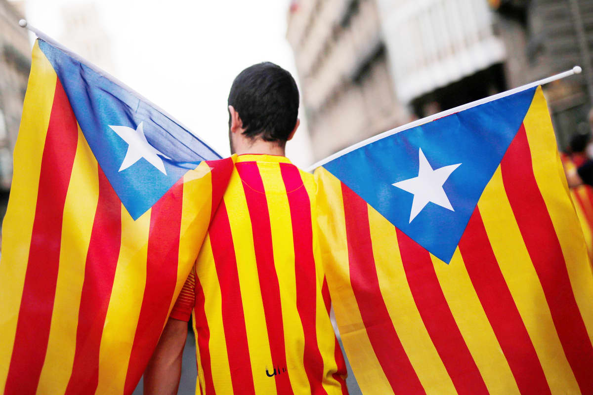 Mies kantaa katalonian lippuja Barcelonassa.