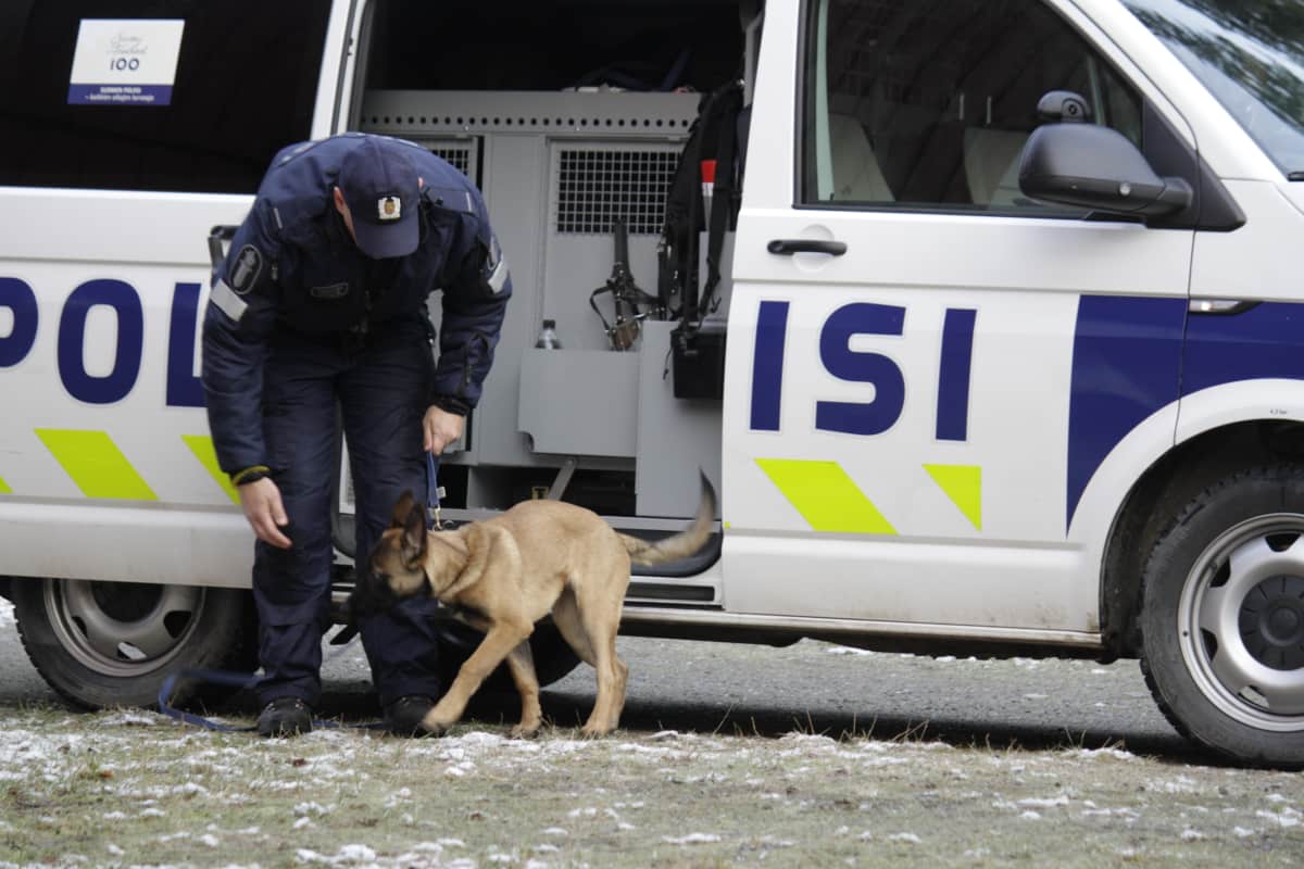 Poliisi ja koira poliisin partioauton edessä