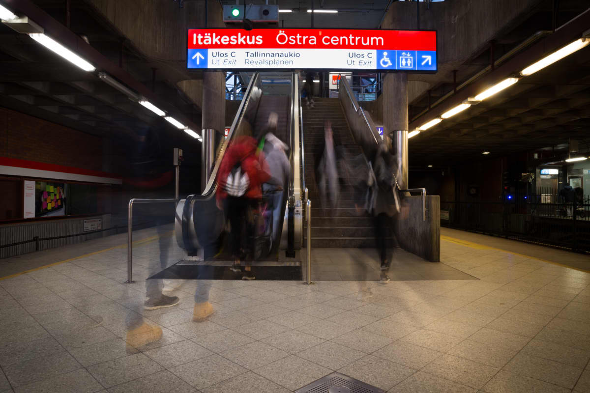 Ihmisiä menee metrolaiturilta rullaportaisiin.