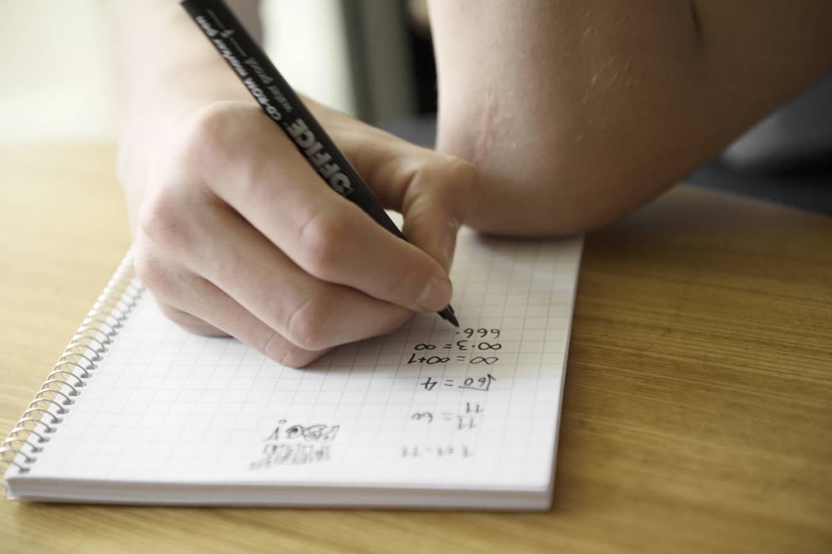 Nuori laskee matematiikan tehtäviä.