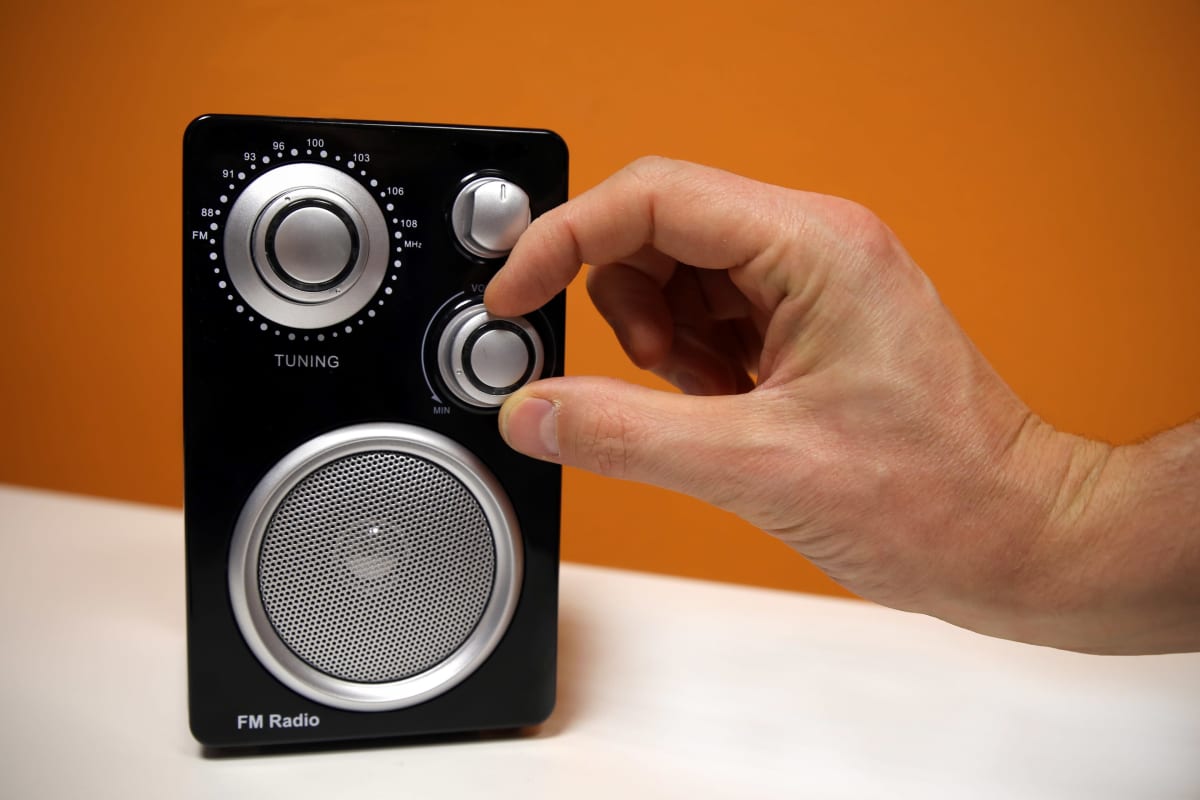 Mies säätää radion äänenvoimakkuutta.