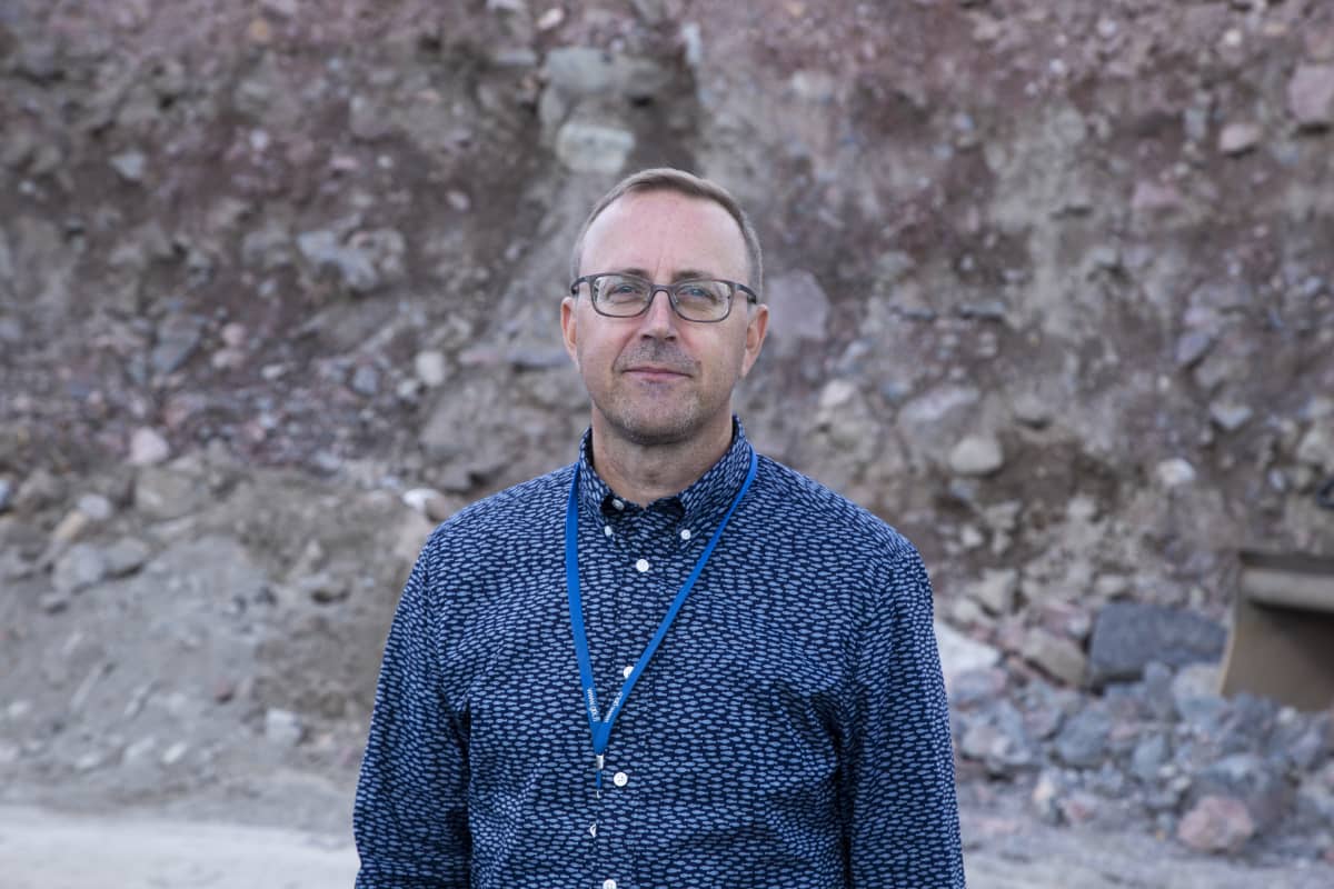 Geologi Jyrki Hämäläinen rakennustyömaalla.Taustalla kivitörmä.