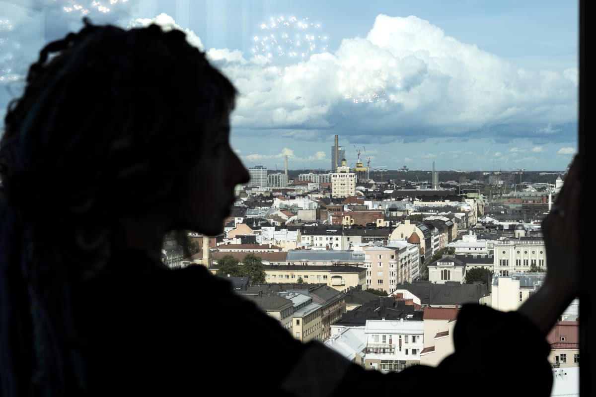 Sofi Oksanen silhuettina Helsingin kaupunkimaisemaa vasten.