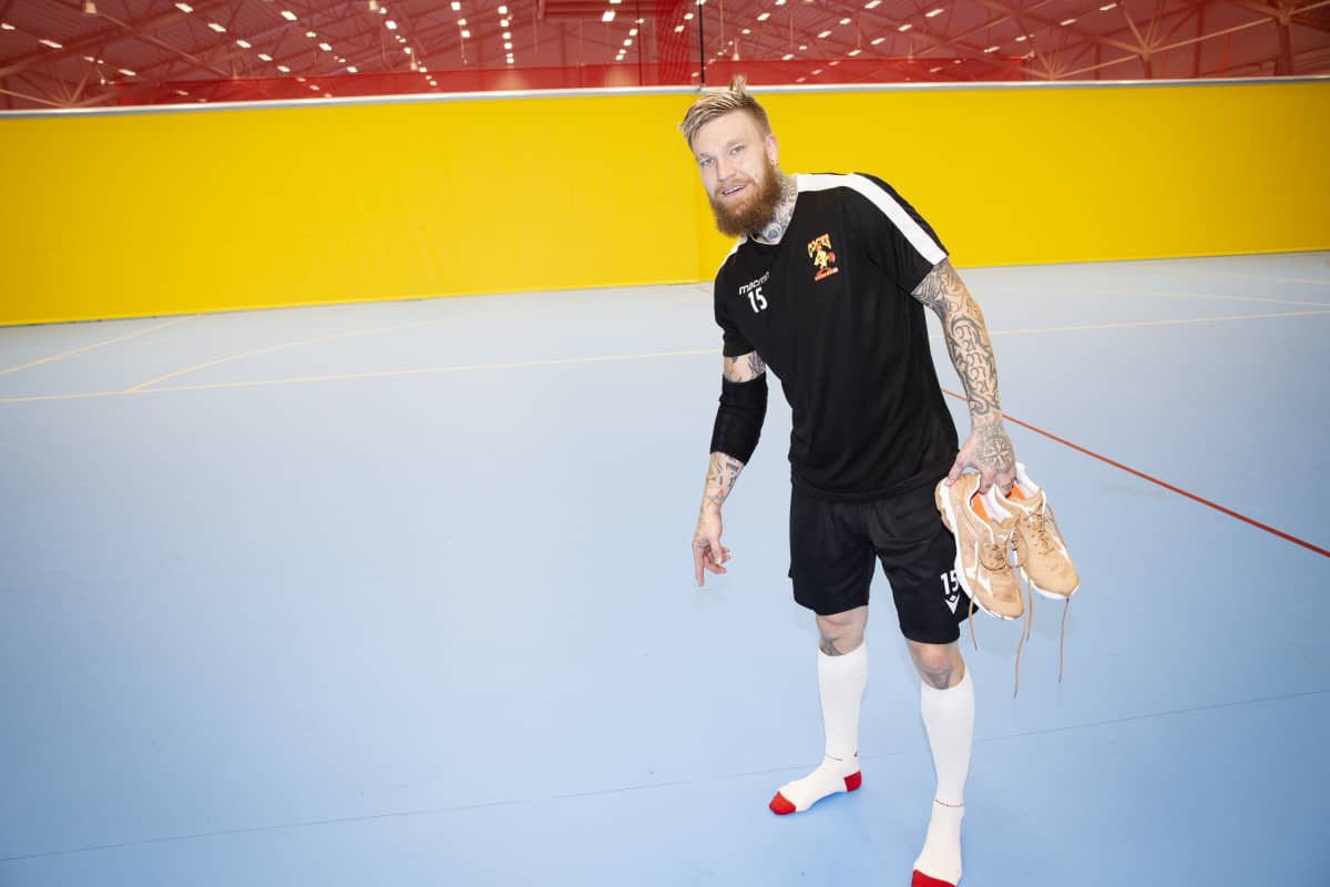 Teemu Tamminen KK osoittaa asentamiensa putkien sijaintia käsipallohallissa. Katse kameraan.