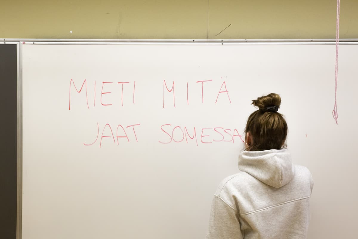 Nuori kirjoittaa luokkahuoneessa taululle: mieti mitä jaat somessa.