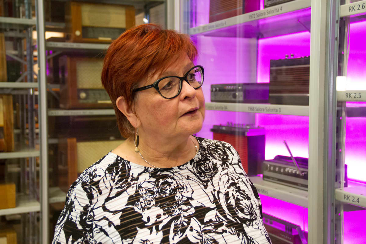 Salon Eletroniikkamuseon tutkija Leena Järvelä katselee hyllyillä olevia radiolaitteita.