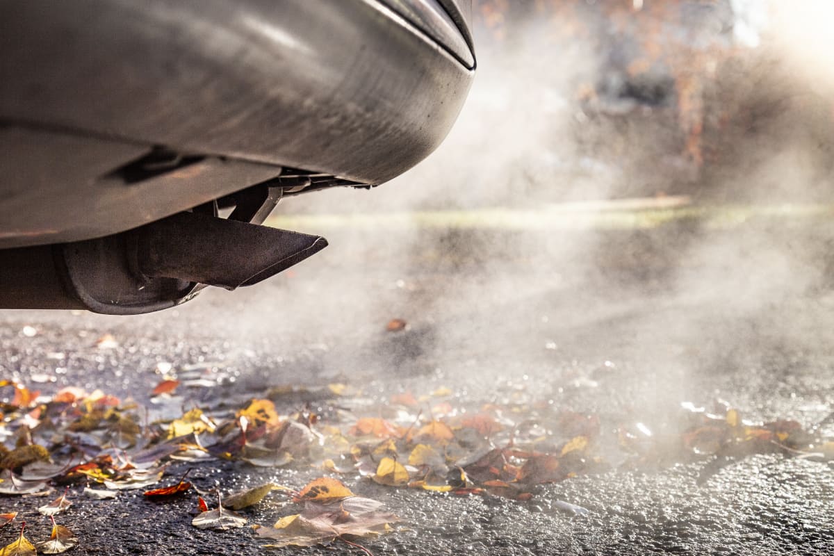 auto ja pakokaasua syksyisessä maisemassa