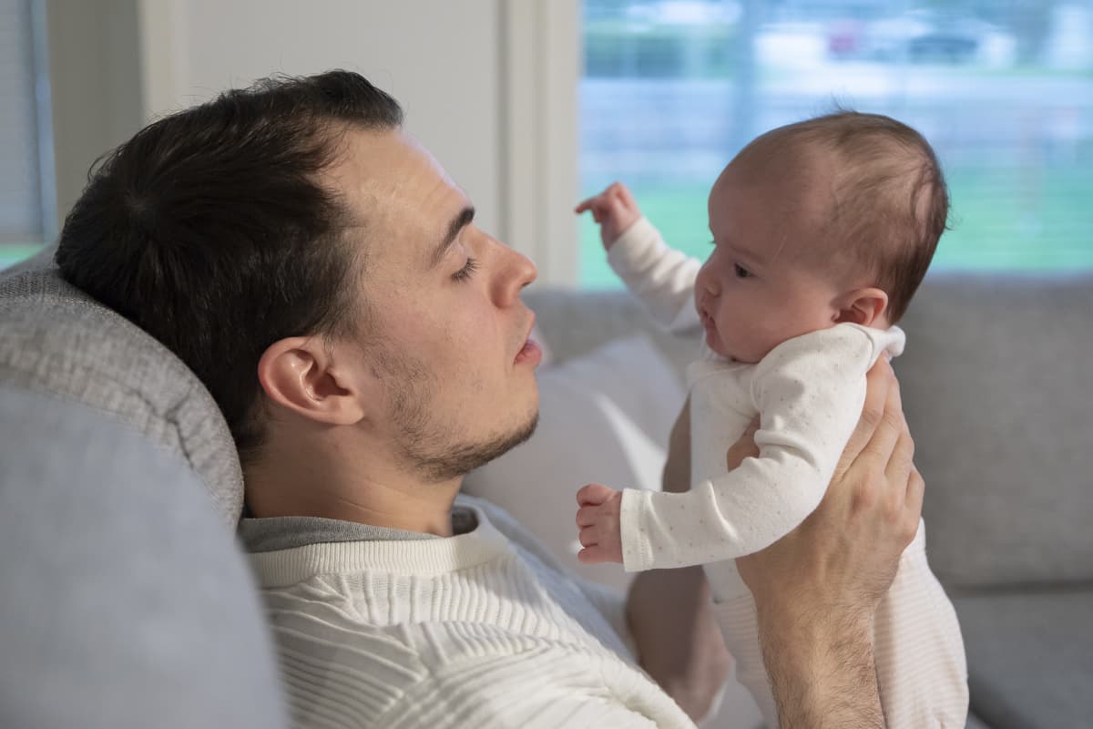 Mies pitelee vauvaa ja molemmat katsovat toisiaan.