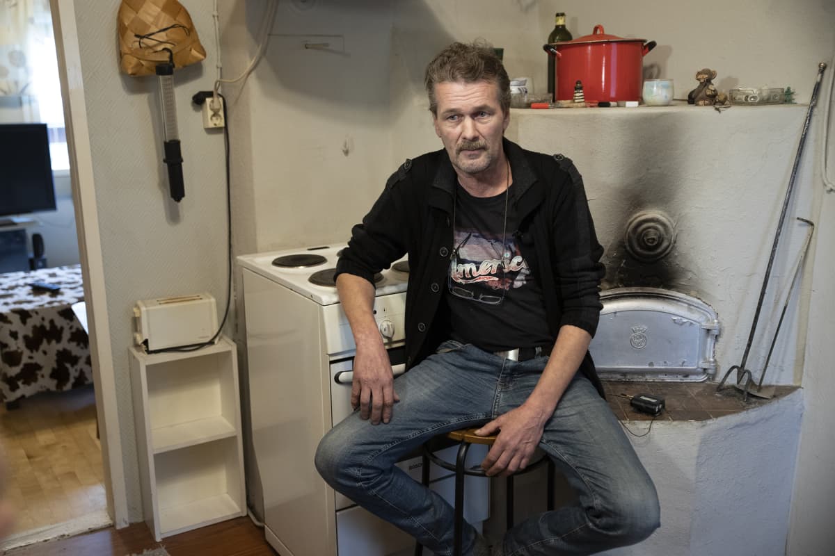 Jari Matikainen istuu hellan edessä keittiössä.
