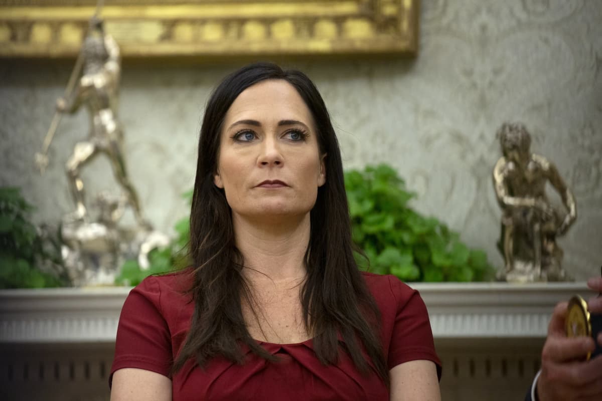 Stephanie Grisham taustallaan kaksi kullanväristä patsasta.