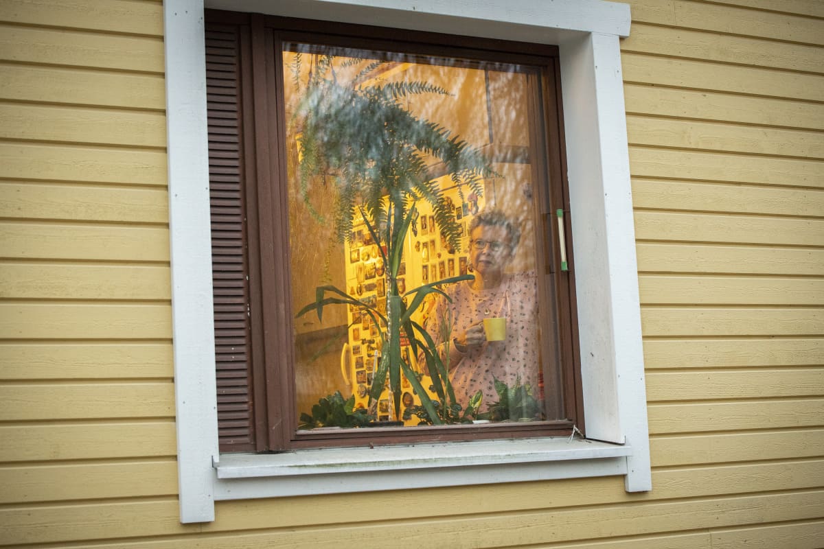 Kuopiolainen Marja Väisänen katsoo ikkunasta ulos.