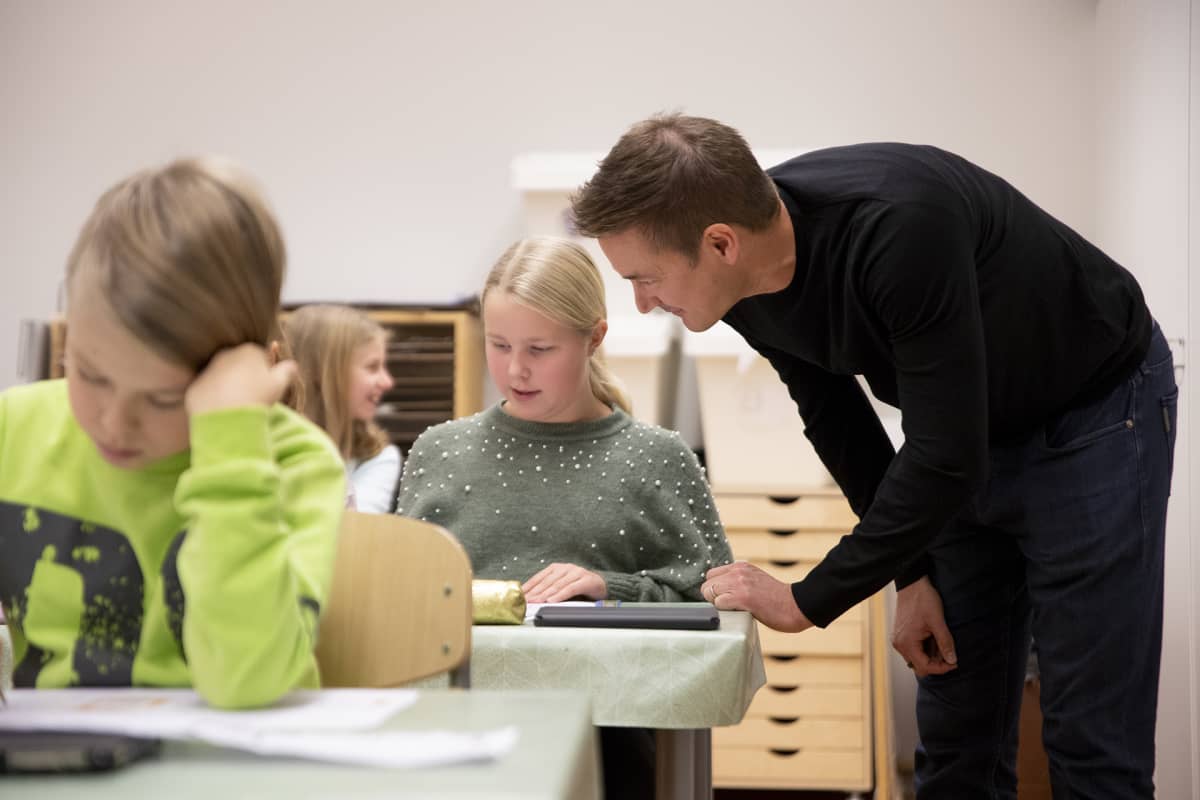 Ilkka Paananen juttelee oppitunnilla tytön kanssa.