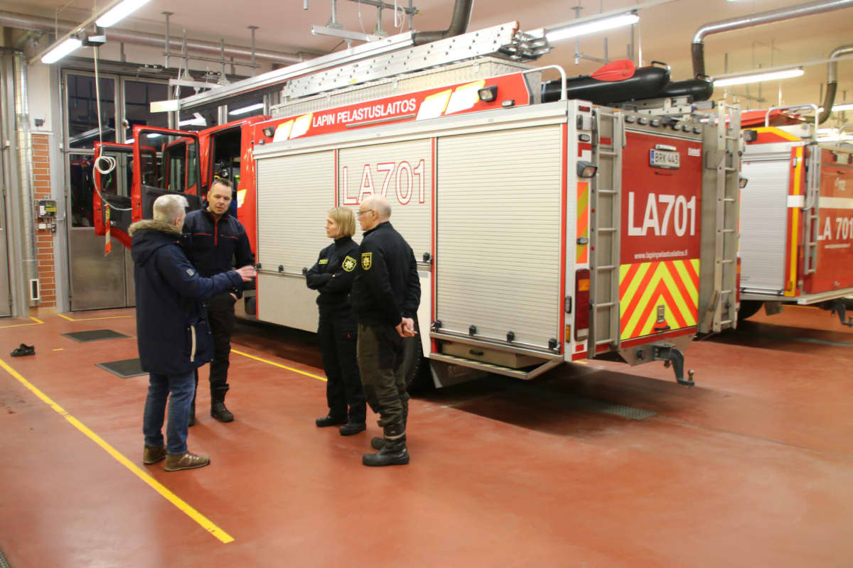 Vilho Varonen, Jussi Pääkkölä ja Maija Kaarninen keskustelevat paloauton luona Sodankylän VPK:n hallissa.
