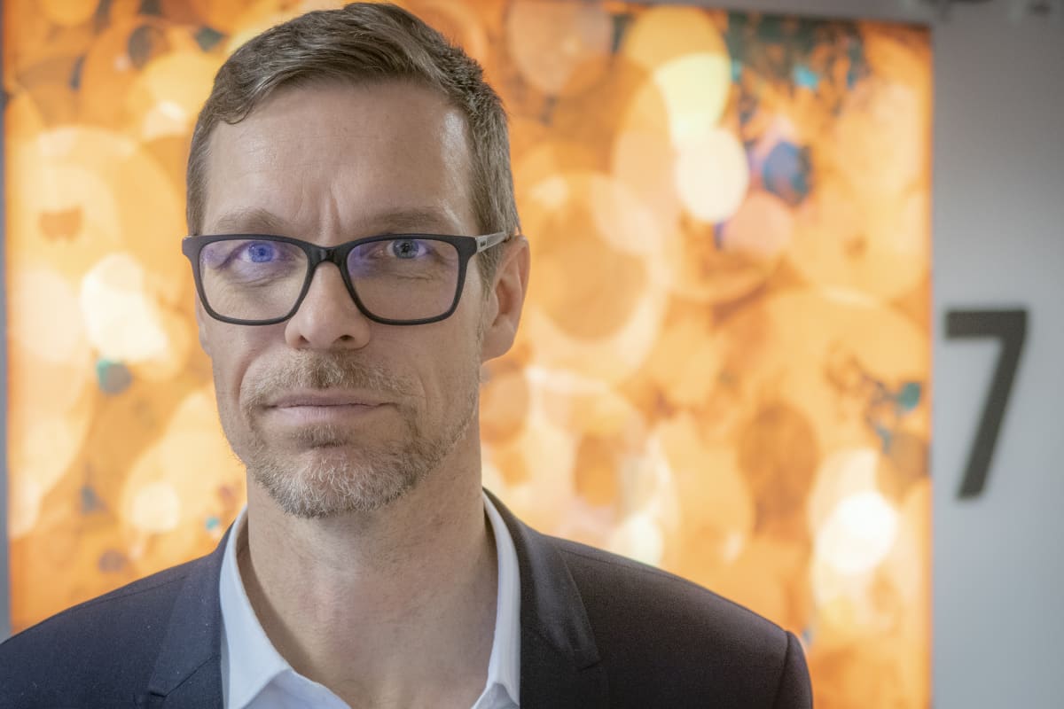 lähikuva Tarmo Martikaisesta keltaisen abstraktimaalauksen edessä