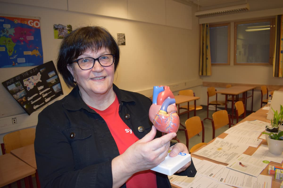 Nainen näyttää sydämen pienoismallia.