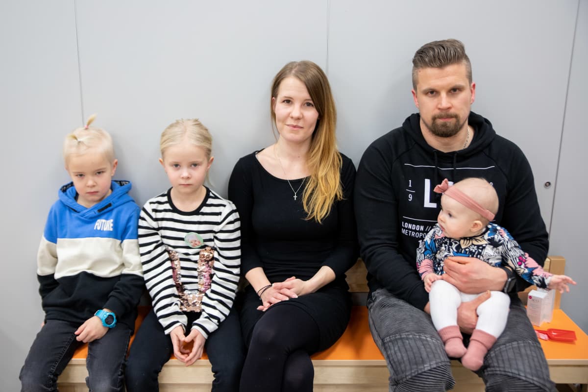 Lapsiperhe istuu penkillä.
