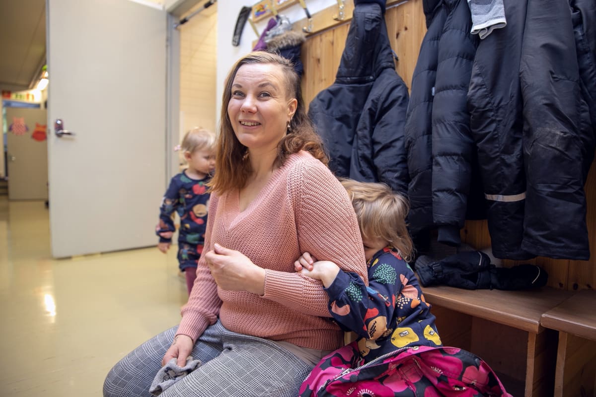 Anu Kosonen istuu tyttäriensä kanssa eteisessä.