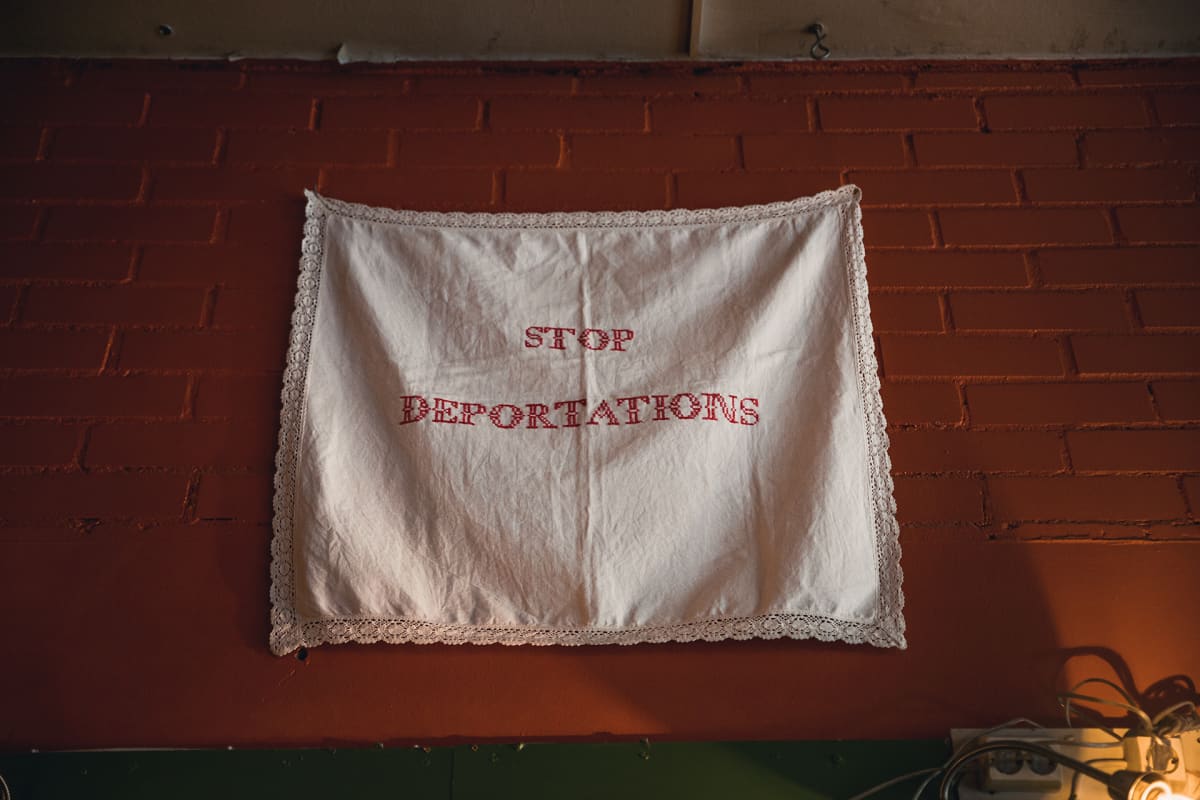 Ristipistotyö " Stop Deportations" Vakiopaineen seinällä.