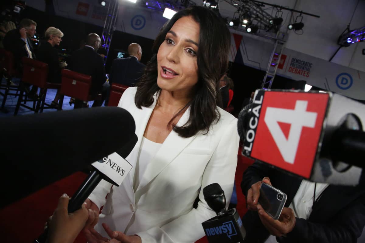 Tulsi Gabbard etualalta työntyvien mikrofonien keskellä