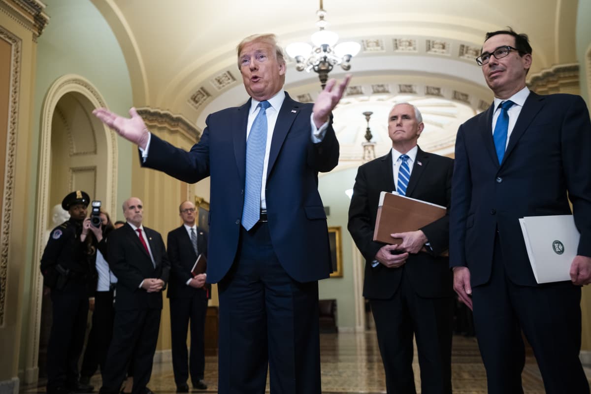 Presidentti Donald Trump levittää käsiään, oikealla puolella varapresidentti Mike Pence ja valtiovarainministeri Steve Mnuchin.