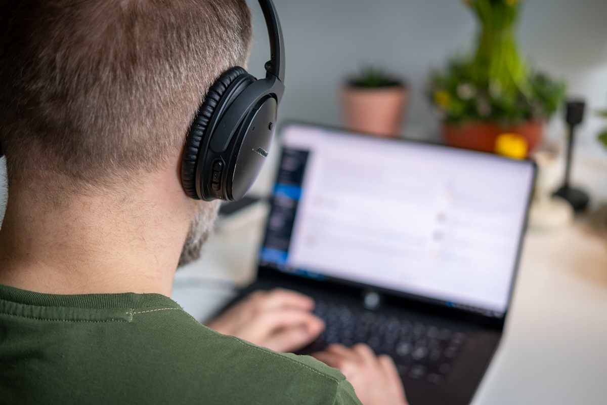 Lähikuva: mies työskentelee etänä kannettavalla tietokoneella.