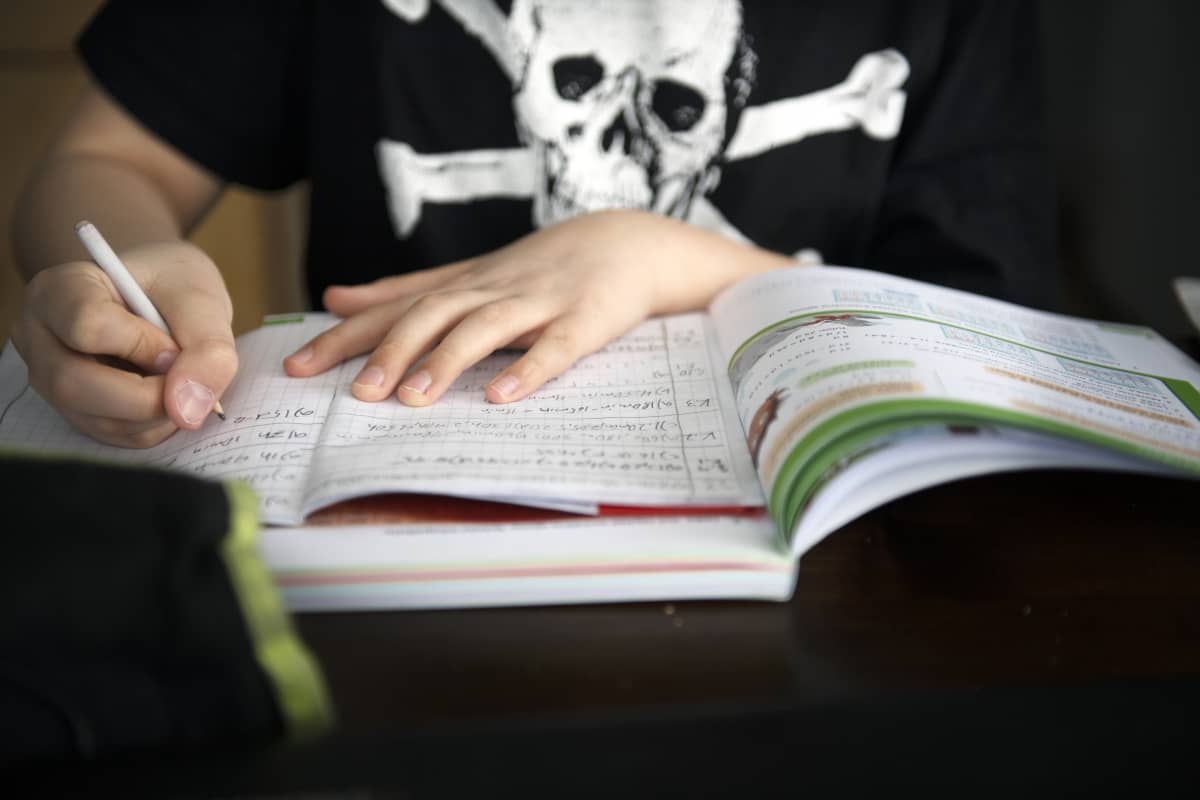 Alakoululainen tekee matematiikan tehtäviä kotonaan.