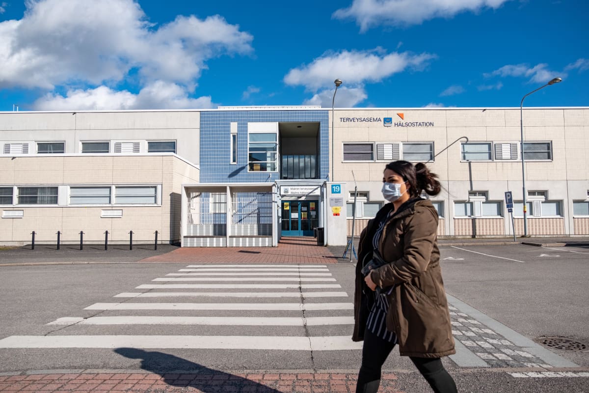 Henkilö kävelee koronaterveysasemaksi muutetun Malmin terveysaseman edustalla 19.3.2020.