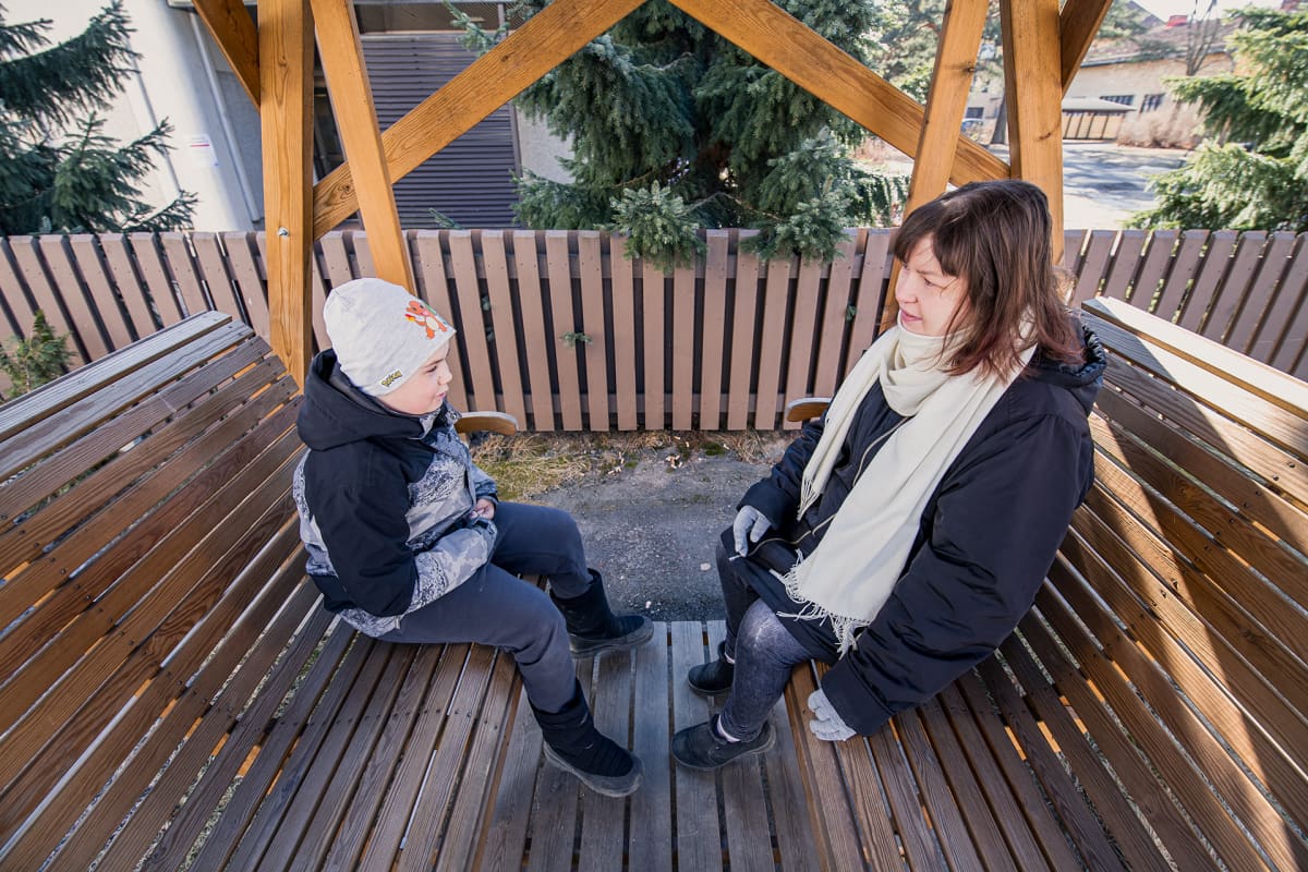 Arja ja poikansa Roope Lehto istuvat pihakeinussa.