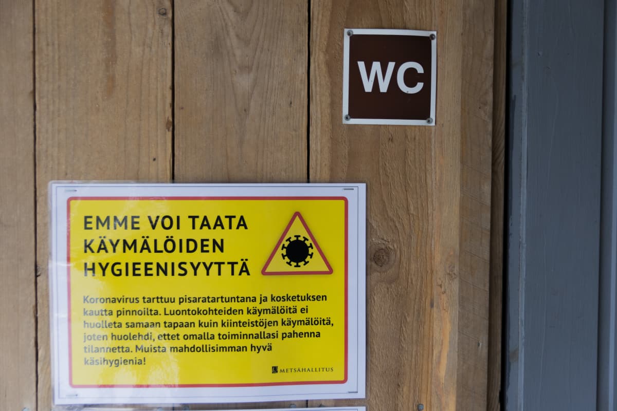 Koronaviruksesta varoittava kyltti Nuuksion kansallispuiston huussissa.
