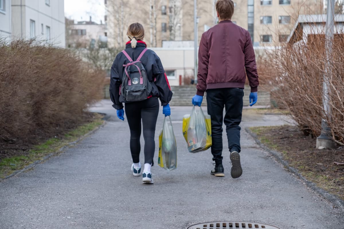 Helsinki-avun vapaaehtoiset Inga Strauss ja Miika Tulkki vievät ruokakasseja vanhuksille.