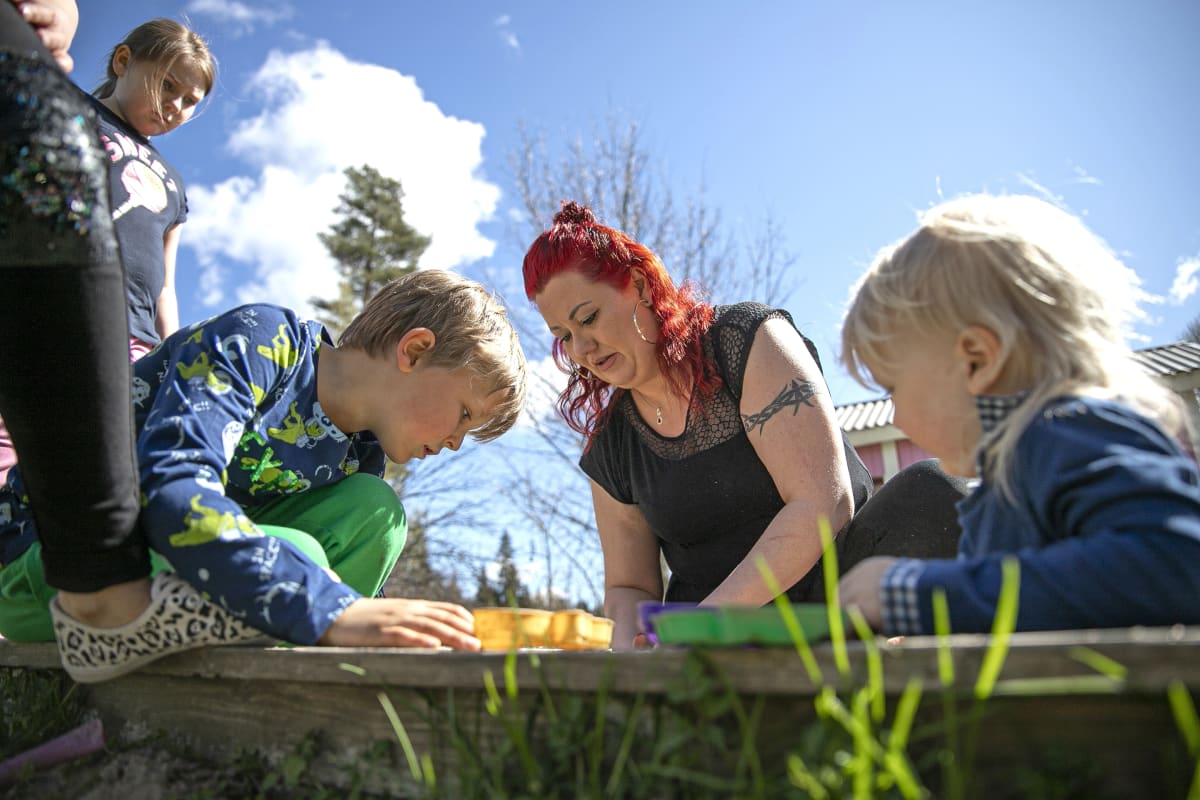 Sanna Salin leilkkii lastensa kanssa hiekkalaatikolla.