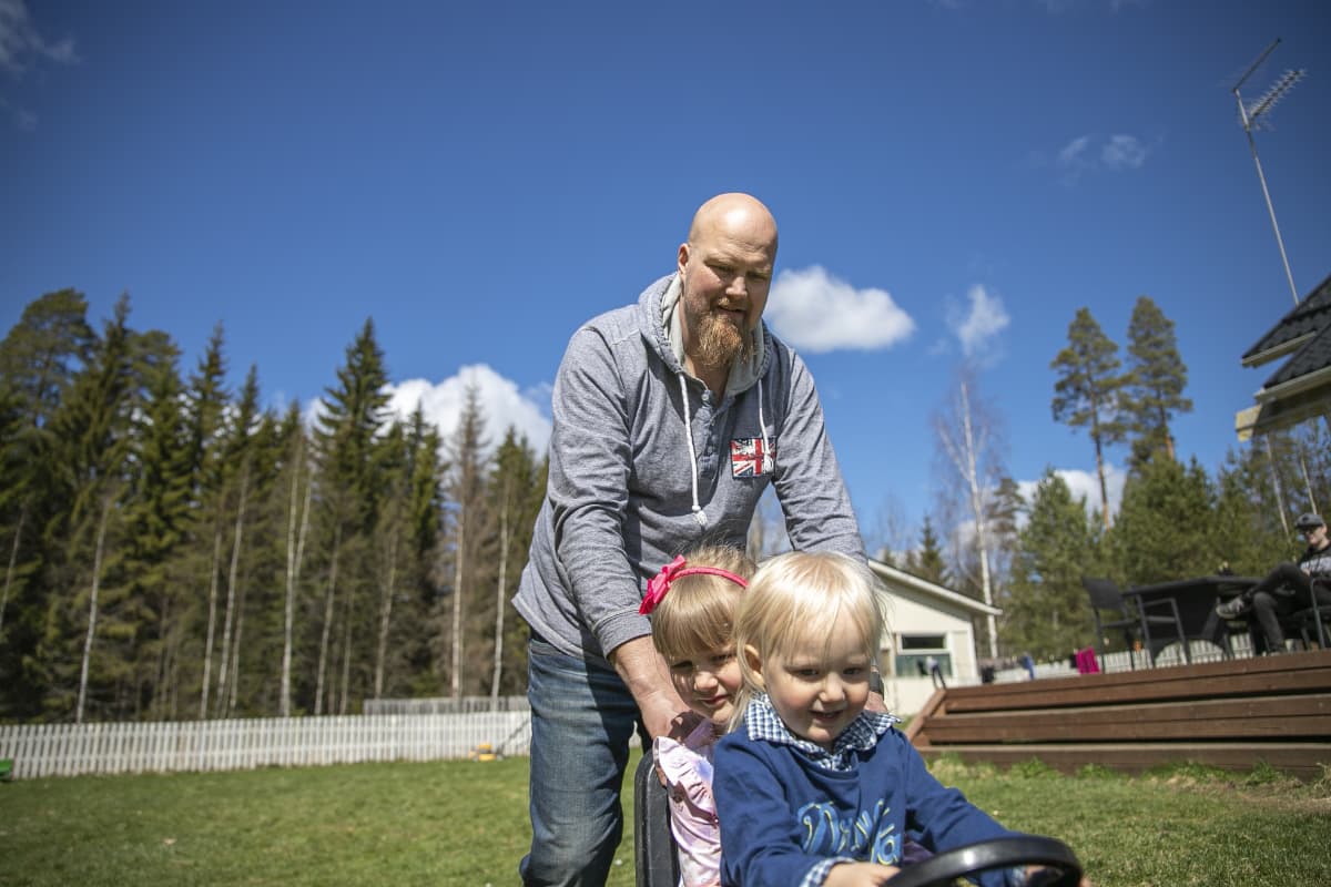Juha Salin työntää kahta lastaan leikkiautossa.
